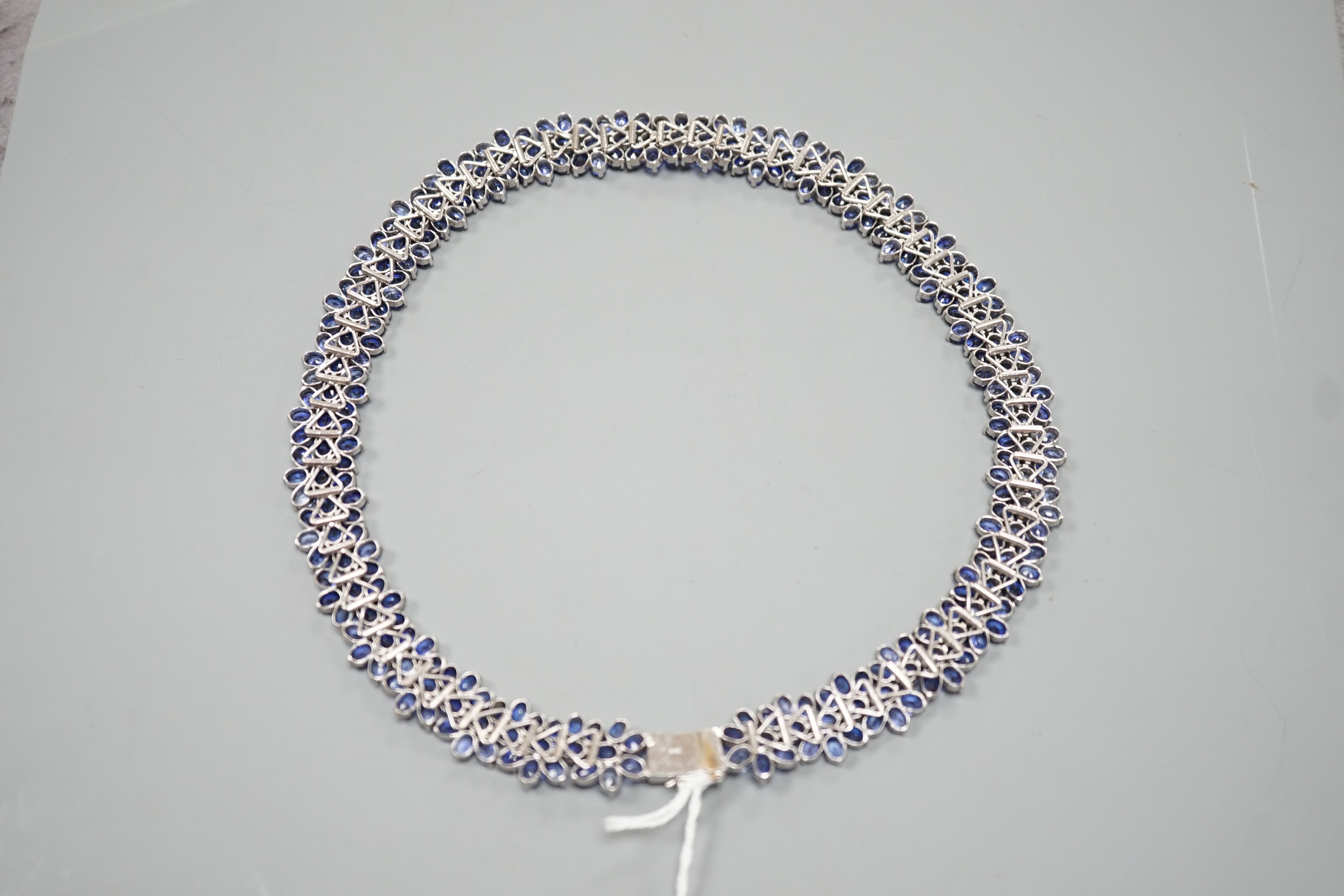 A continental base metal and synthetic sapphire? flower head cluster set necklace, approximately 39cm.